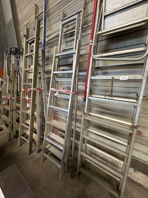 several ladders are lined up against a wall in a warehouse