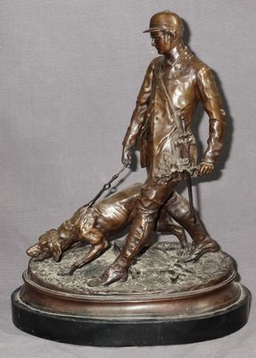 statue en bronze représentant un homme accompagné d'un chien et d'un chat, posée sur un socle en marbre