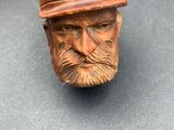 a wooden head of a man with a hat and a pipe