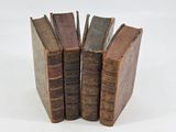 several old books stacked on top of each other on a white surface