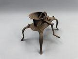 an antique brass candle holder on a stand with a hat on top
