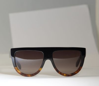 des lunettes de soleil noires et écaille posées sur une surface blanche, sur fond blanc