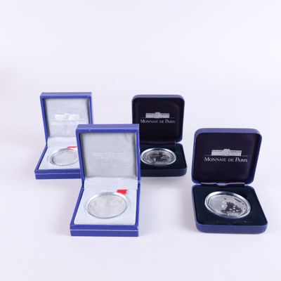 three silver coins are in a blue case and a silver coin is in a blue box