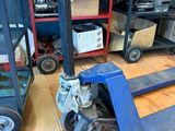 a blue hand truck sitting next to a stack of boxes on a wooden floor