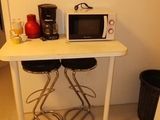 a small table with two stools and a microwave on top of it