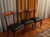 trois chaises placées devant un rideau dans une pièce