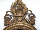 a gold clock with a basket of grapes on top of it