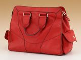 red leather handbag on a white surface with a beige background