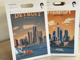 detroit, michigan and new york city travel posters on a wooden table