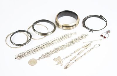 de nombreux bracelets et bagues en argent posés sur un fond blanc