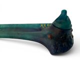 a glass spoon with a green handle on a white surface
