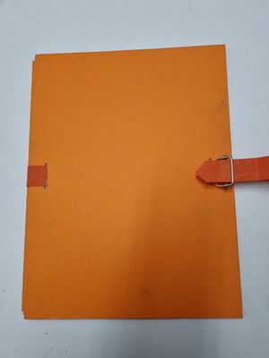 a close up of a piece of orange paper with a buckle on it