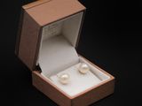 une boîte ouverte contenant une paire de perles, sur fond noir