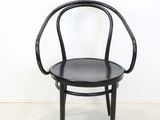 black bent bent chair against a white wall in an empty room