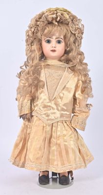 an antique doll with blonde hair wearing a gold dress and hat