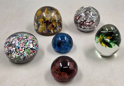 six billes de verre posées sur une surface blanche
