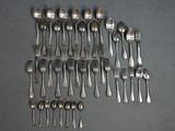 un grand nombre de cuillères et de fourchettes en argent disposées sur une table