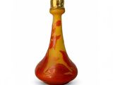 une bouteille en verre rouge et jaune avec un bouchon doré