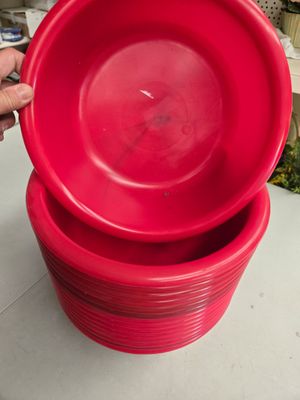 une personne tenant une pile d'assiettes rouges sur une table