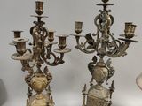Plusieurs chandeliers anciens en argent sont posés sur une surface blanche