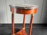 une vieille table en bois avec un plateau en marbre, posée sur un sol carrelé