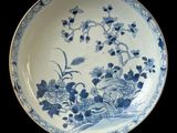 blue and white plate with flowers and birds on it on a stand