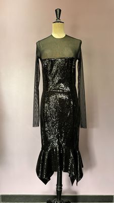 robe noire à paillettes posée sur un mannequin devant un mur rose