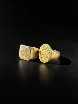 a pair of gold rings with initials on them on a black surface
