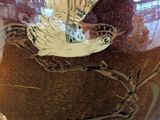a brown vase with a bird on it on a stand