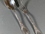 two silver spoons and a fork on a table