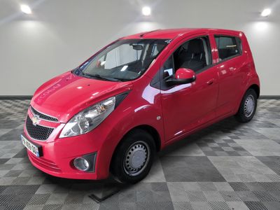 the small red car is parked on a checkered floor