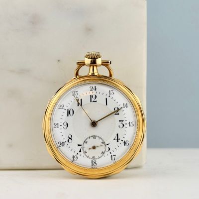 une montre de poche en or posée sur un bloc de marbre