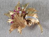 une broche en or ornée de pierres rouges et blanches