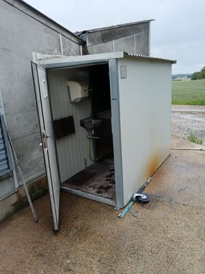 des toilettes situées dans l'embrasure de la porte d'un petit bâtiment