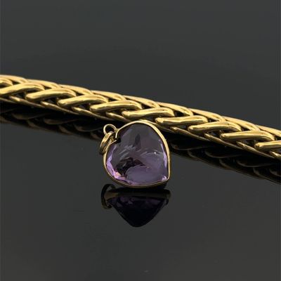 a close up of a gold chain with a purple stone on it