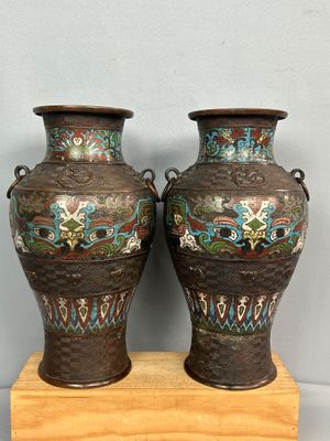 Deux vases sont posés sur un socle en bois adossé à un mur.