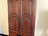 a wooden armoire in the corner of a room