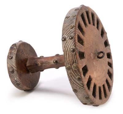 an old wooden wheel with holes on it sitting on a white surface