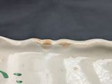 a close up of a white bowl with a green flower on it