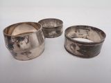 three silver napkins and a bowl on a white surface