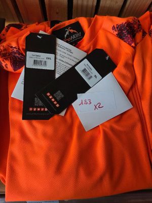an orange shirt sitting on top of a wooden bench next to a pair of scissors