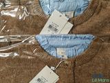 two sweaters with tags on them sitting on a plastic bag