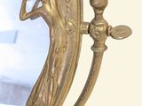 a gold mirror with a woman holding a candle on it