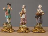 three figurines of people are standing on pedestals on a table