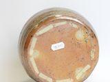 a brown vase sitting on a white surface with a label on it