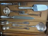 a lot of silver spoons and spoon knives in a box