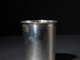 an empty silver cup on a dark surface with a black background