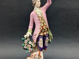 an antique figurine of a man with flowers and a dog