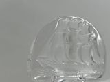 a glass sculpture of a ship on a white surface