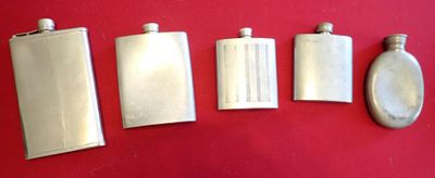 four silver flasks lined up on a red surface